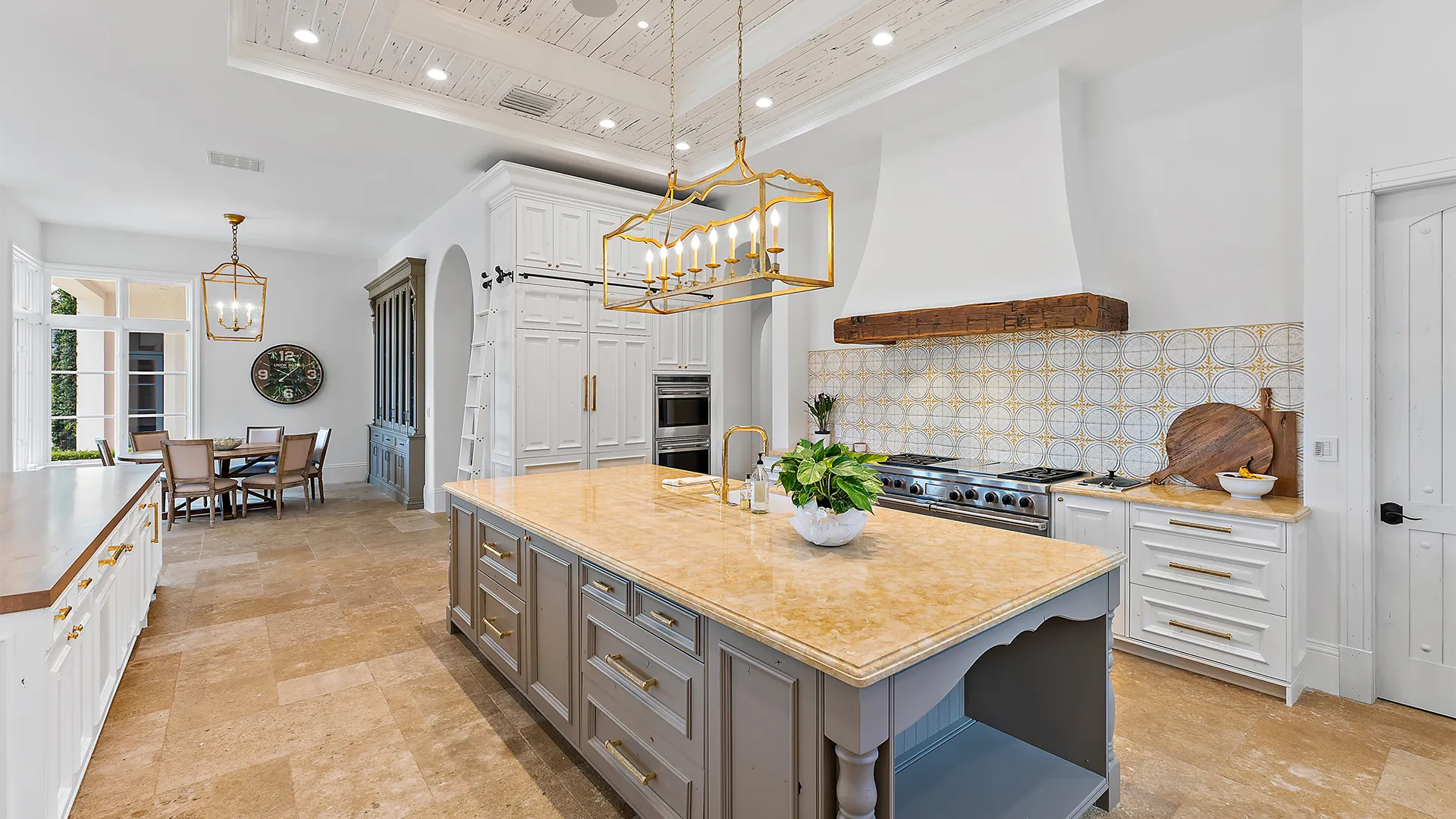 Kitchen design with a large island and dining area, featuring refined gold, grey, and white accents.