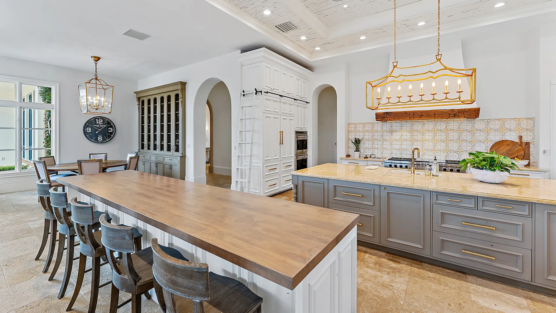 Kitchen design with a large island and dining area, featuring refined gold, grey, and white accents.