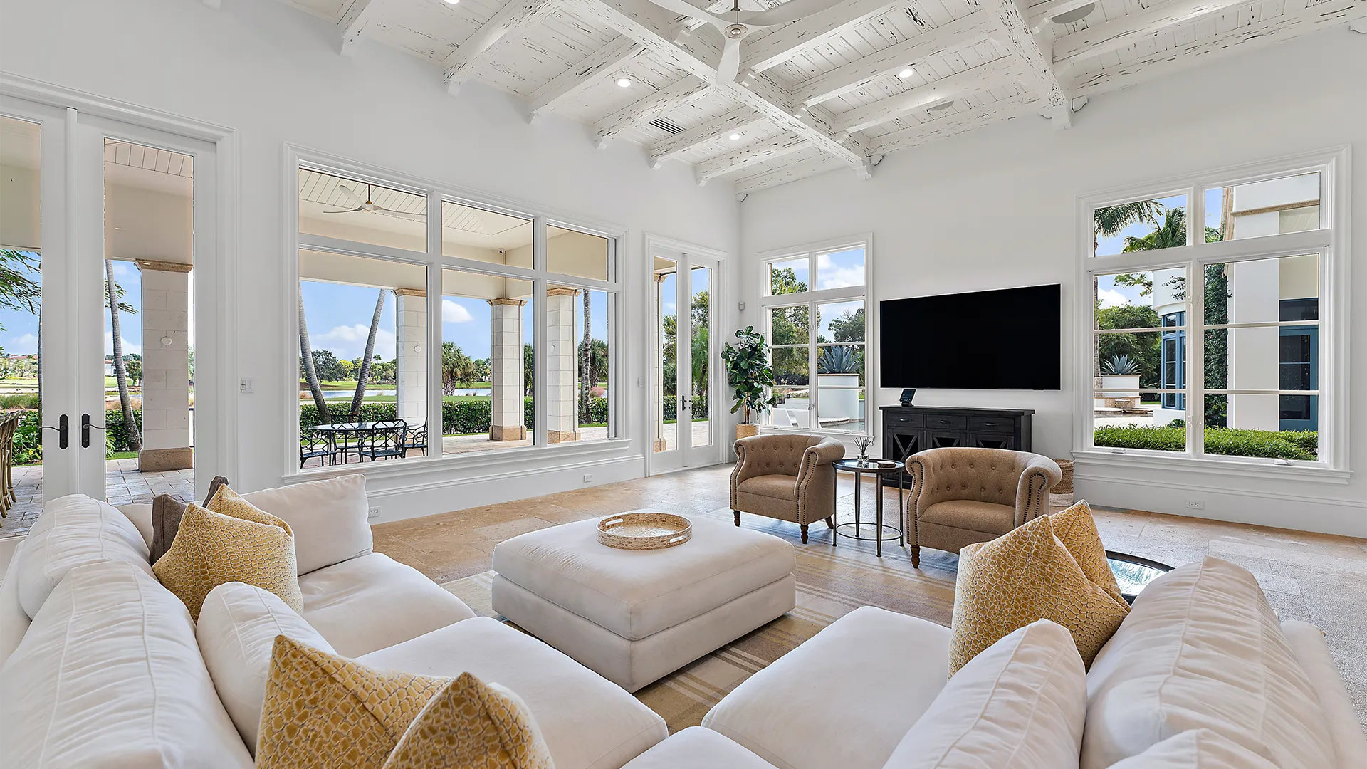 Trendy living room crafted with refined white furnishings and a contemporary television.