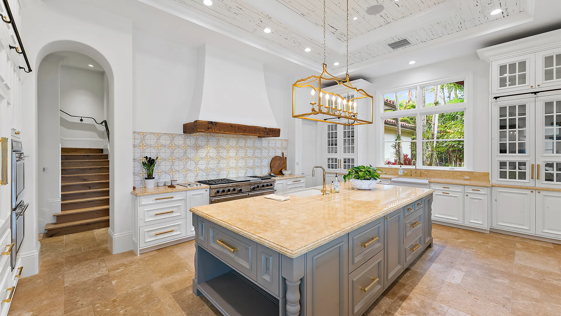 Kitchen design with a large island and dining area, featuring refined gold, grey, and white accents.