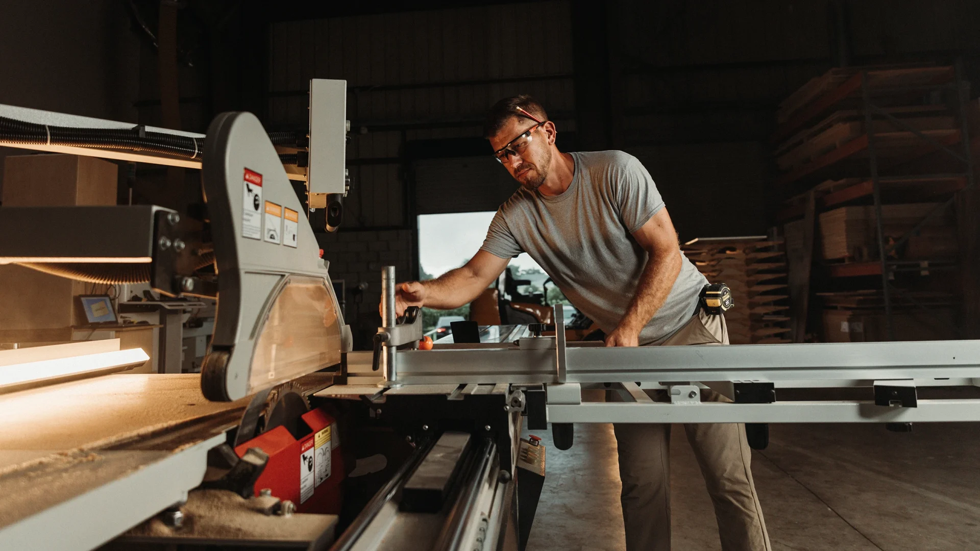 Man operates a woodworking machine, focused on crafting wood into precise shapes and designs in a workshop setting.