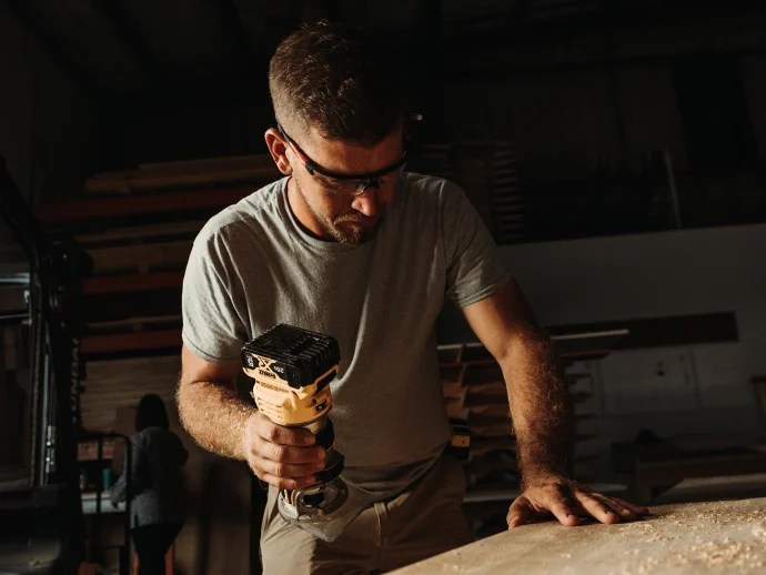 Man drills into a piece of wood, focusing on precision in his woodworking task.
