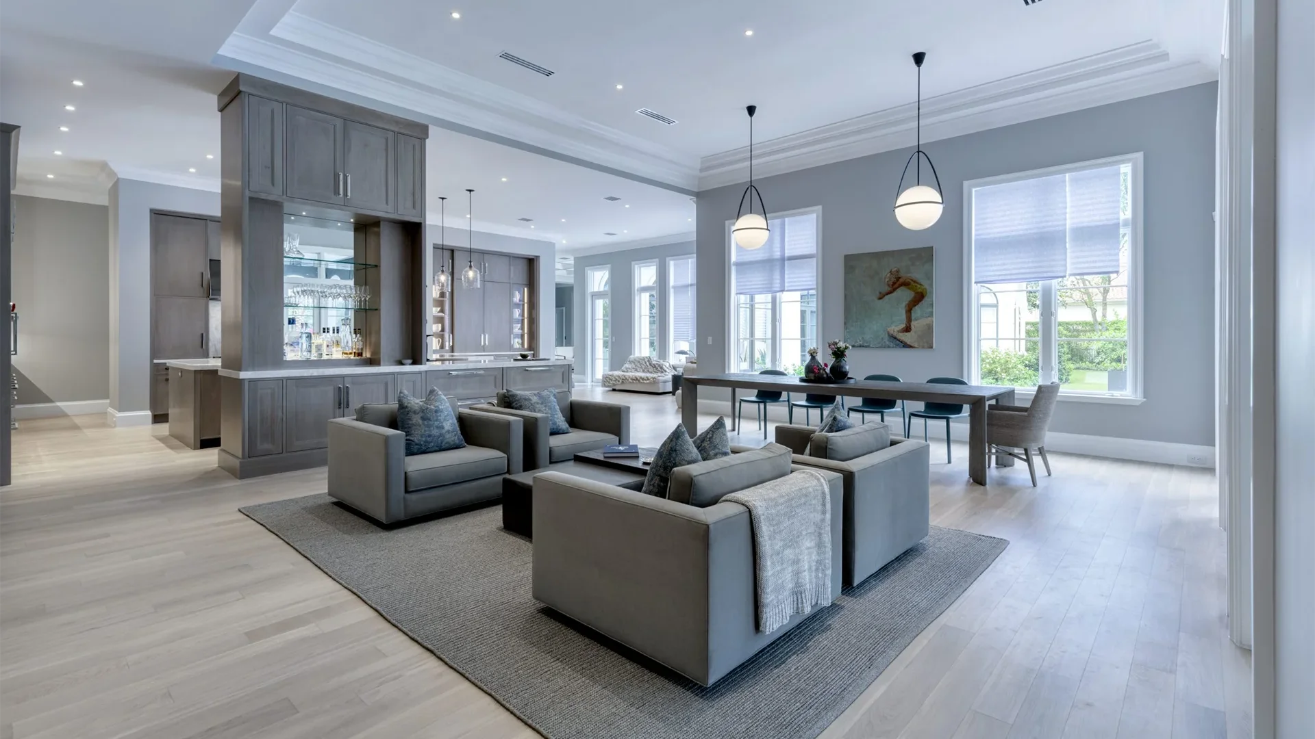 Sleek modern living room adorned with gray furnishings, adjacent to a well-designed kitchen space.