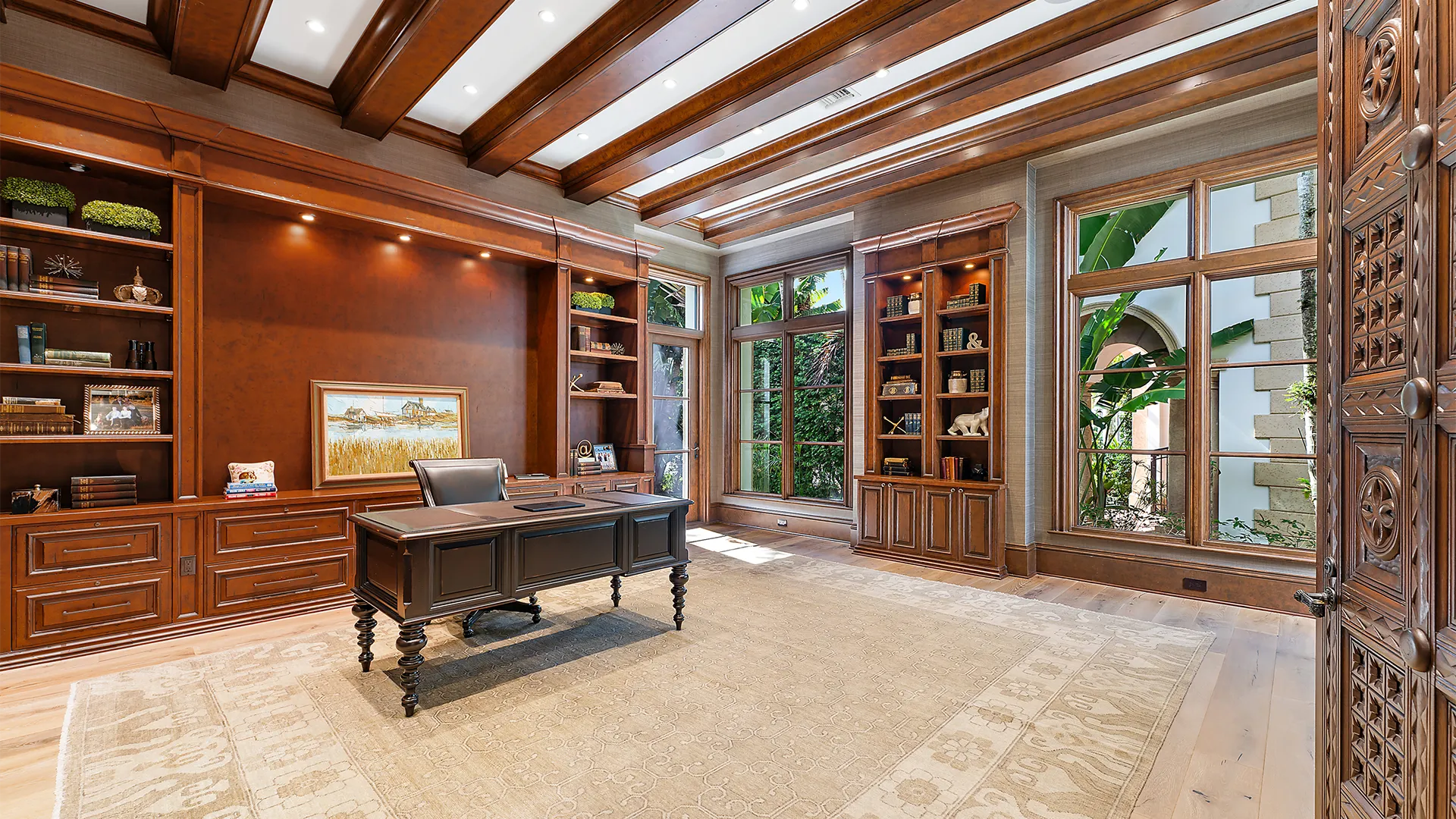 Sophisticated home office featuring elegant wooden beams, a stylish desk, and plush carpet furnishings.