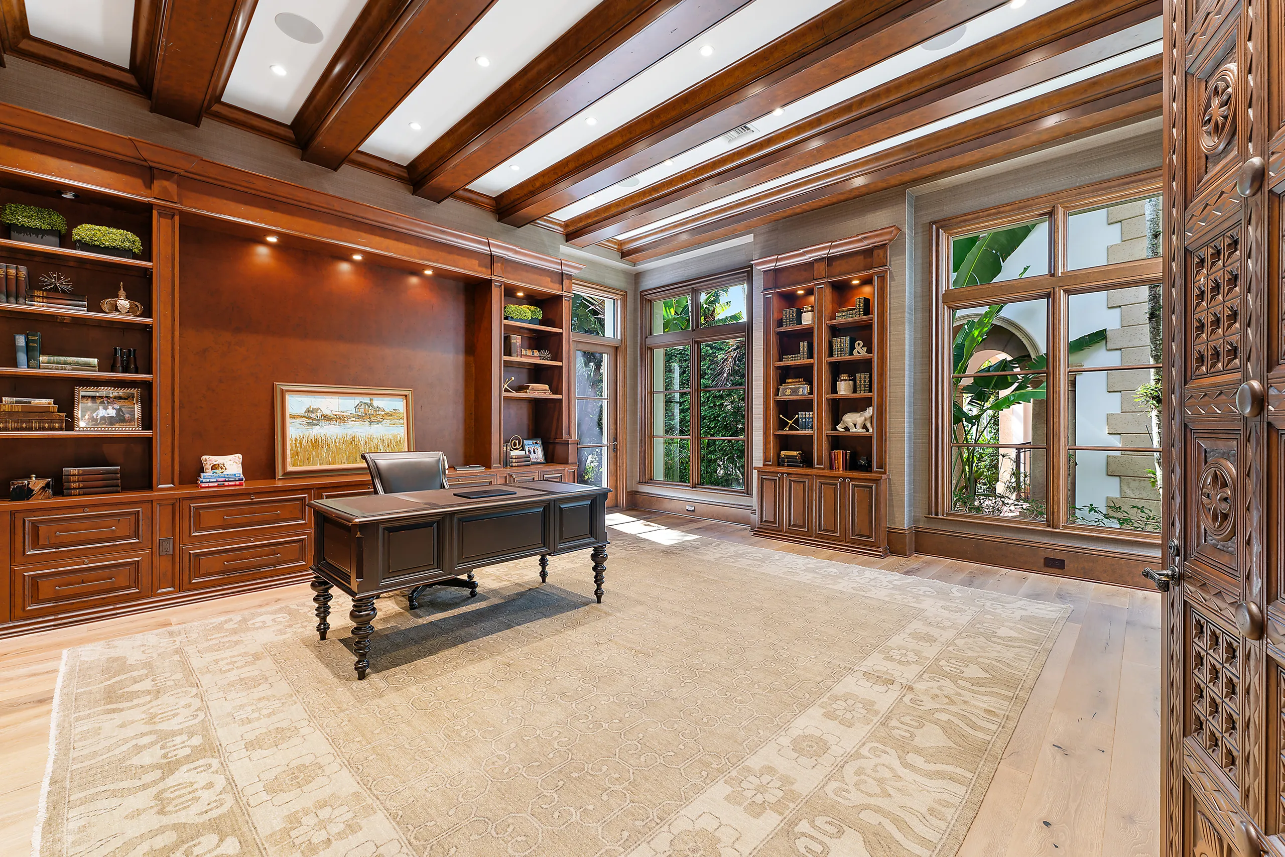 Sophisticated home office featuring elegant wooden beams, a stylish desk, and plush carpet furnishings.