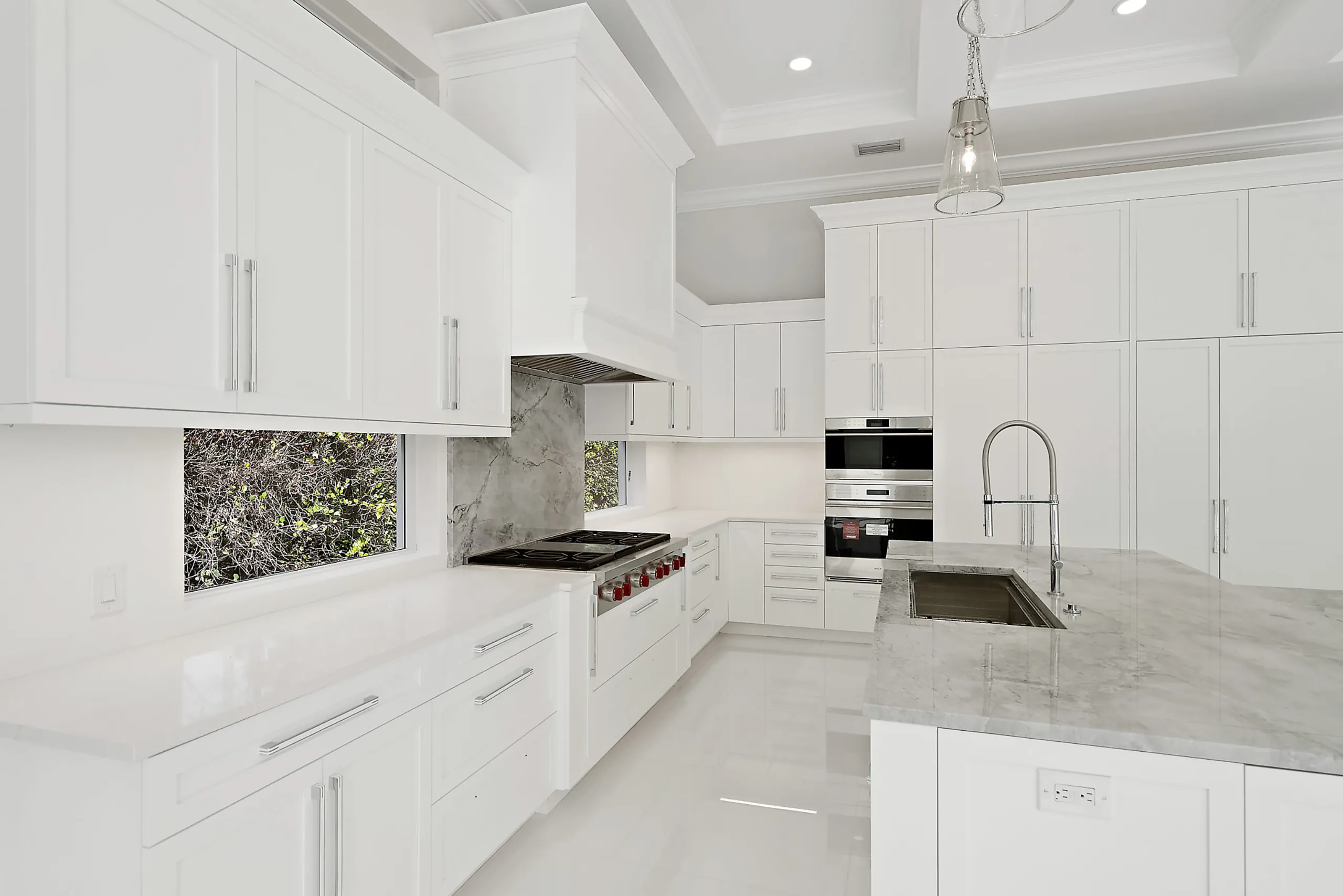 Grand white kitchen highlighted by opulent marble countertops.