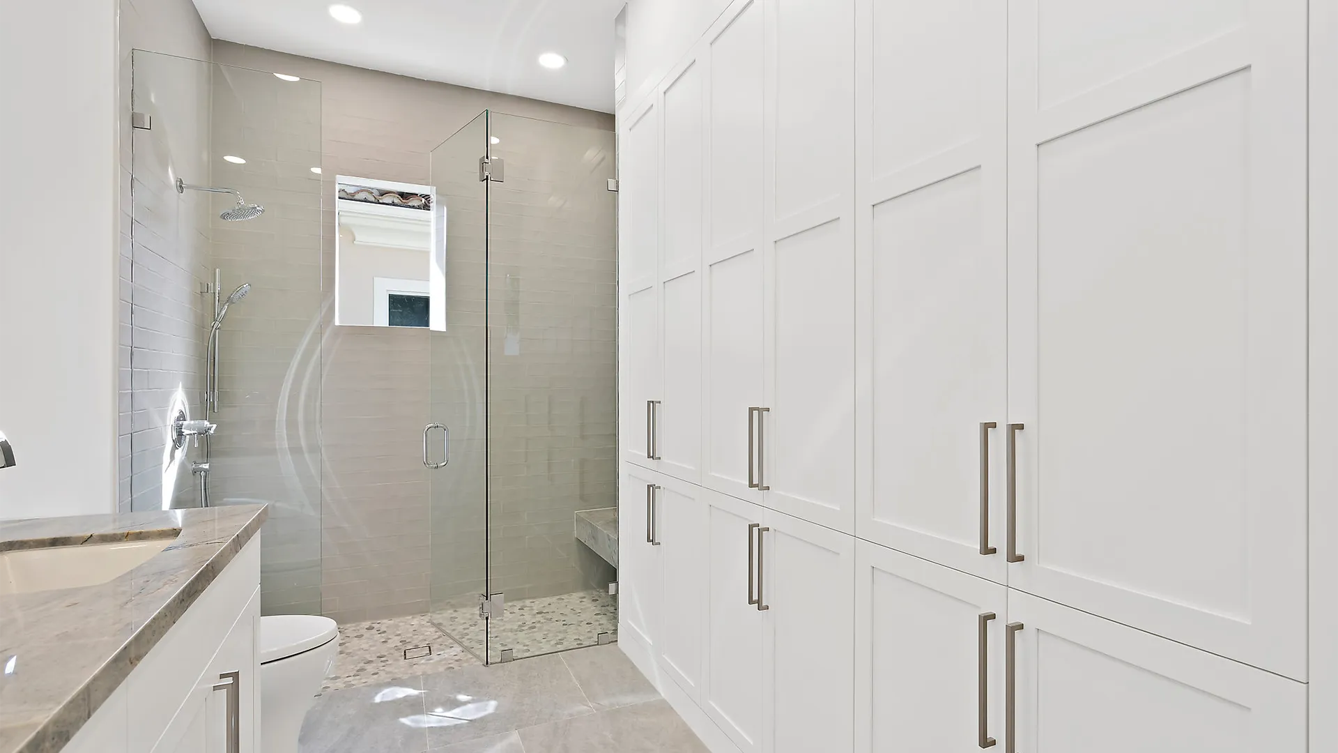 Extravagant bathroom embellished with immaculate white cabinets and a contemporary glass shower.