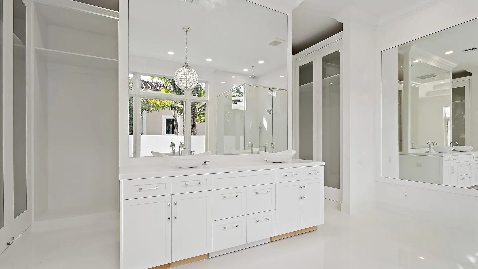 Grand bathroom with immaculate white cabinets and large mirror.