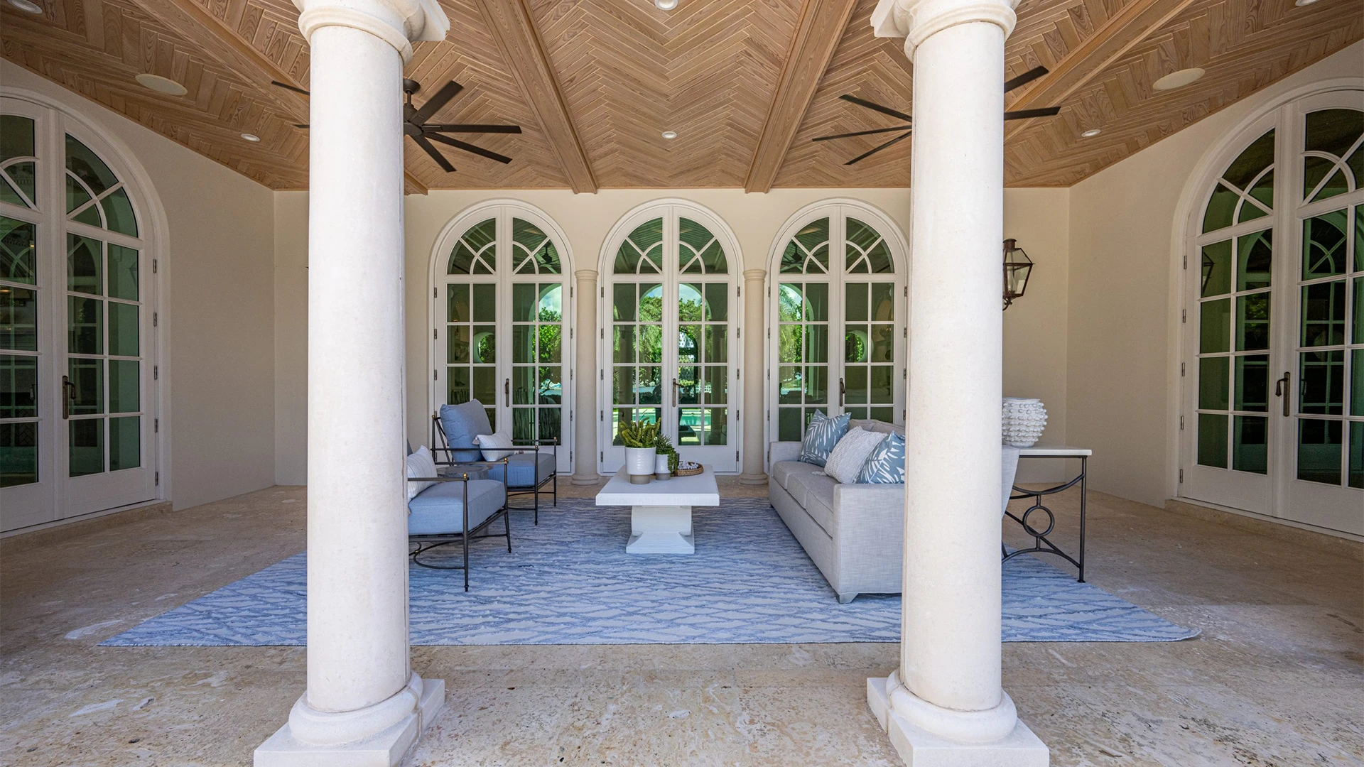 Grand covered porch adorned with elegant columns, featuring a serene blue rug that invites relaxation and luxury.