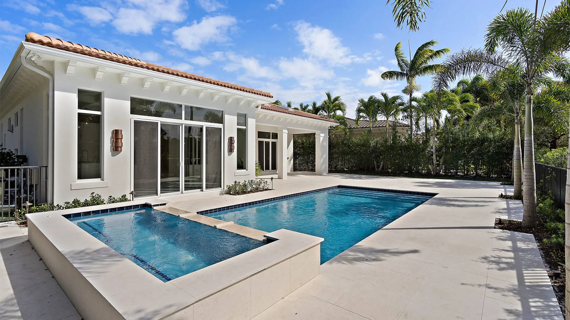 Serene pool glistens in front of a Coastal Contemporary style modern home, framed by vibrant palm trees that sway softly in the wind.
