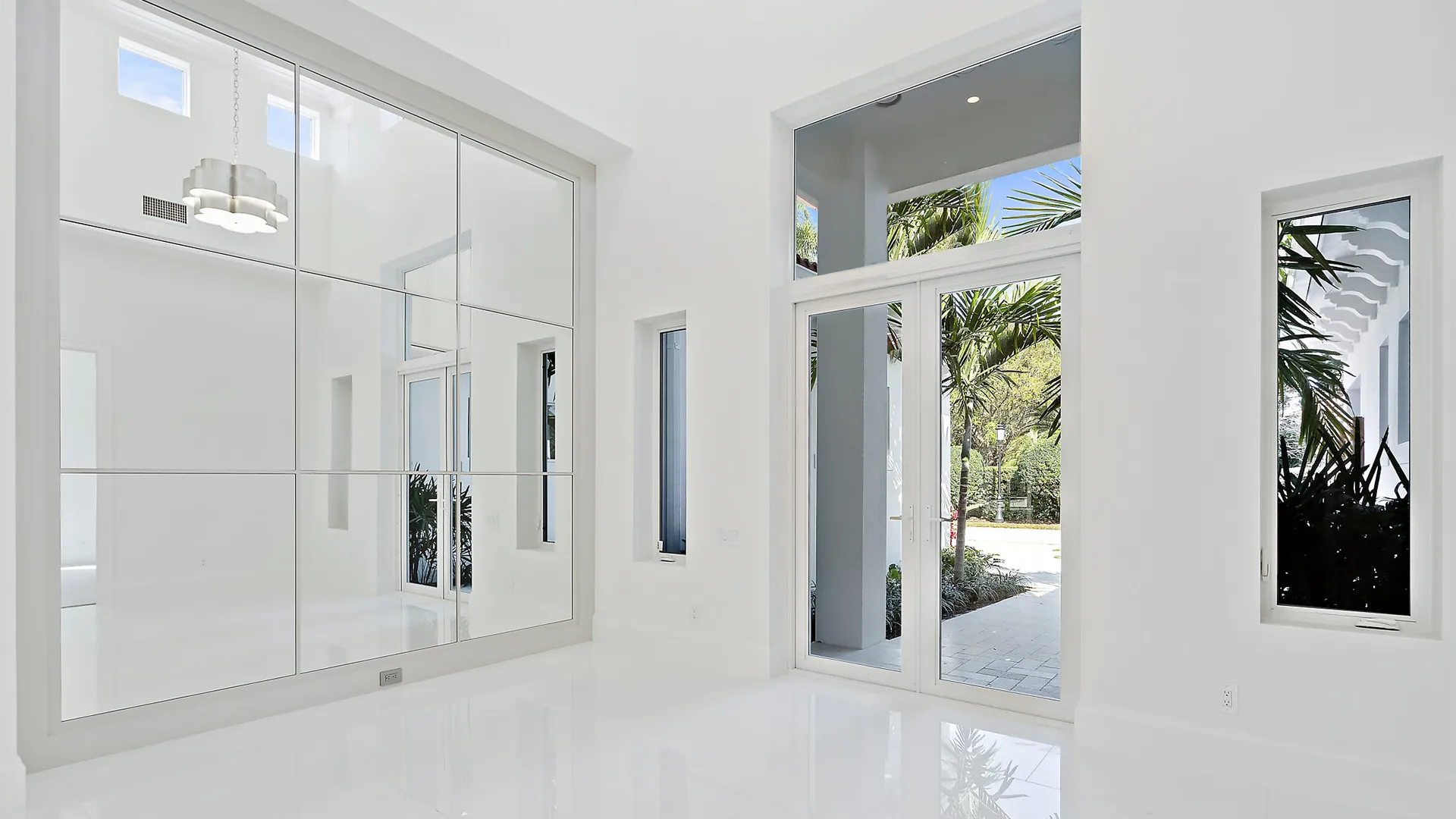 Minimalist white hallway showcasing mirrored walls and a large mirror.