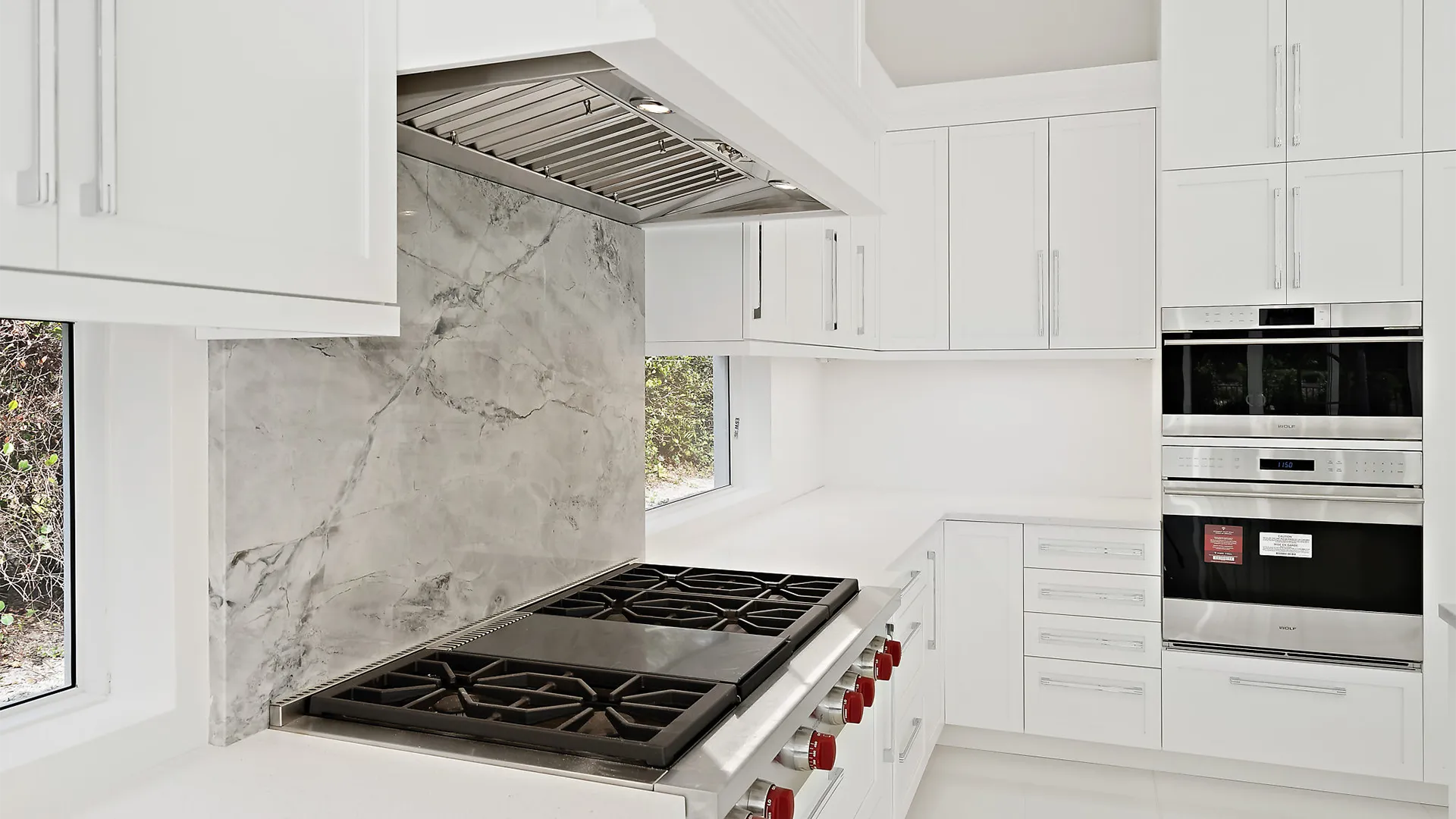 Large and airy kitchen with sleek white finishes and exquisite marble countertops.