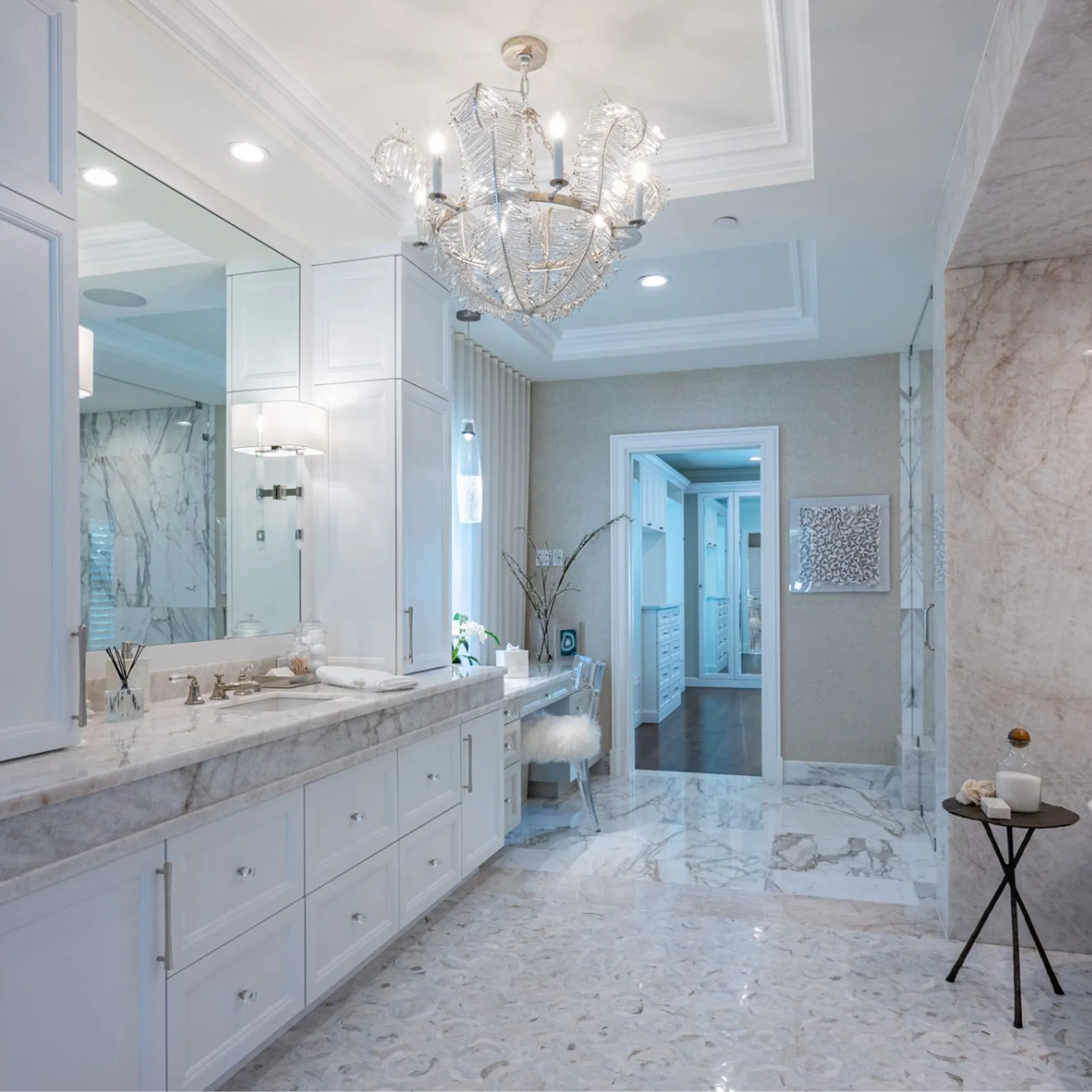 Bathroom with polished marble countertops and an ornate chandelier.