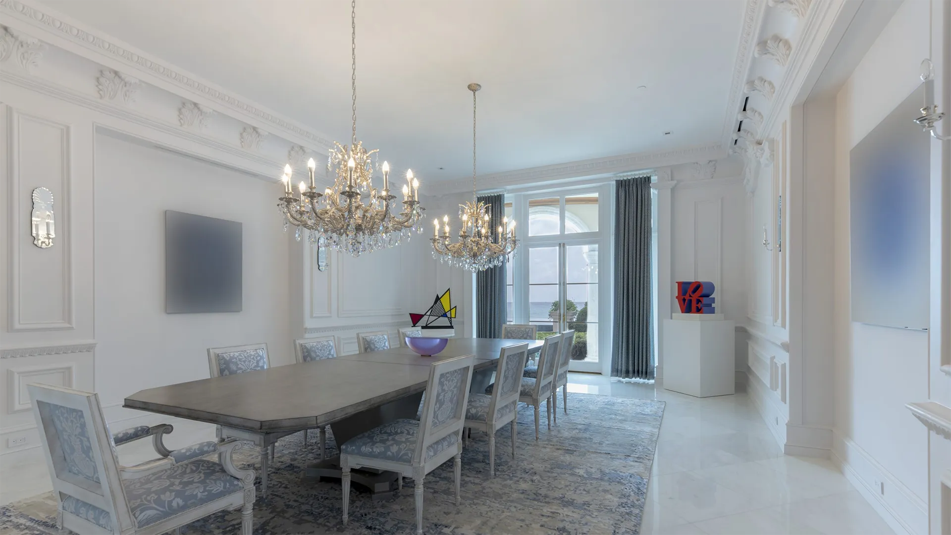 Living room highlighted by a magnificent chandelier and stylish couches.