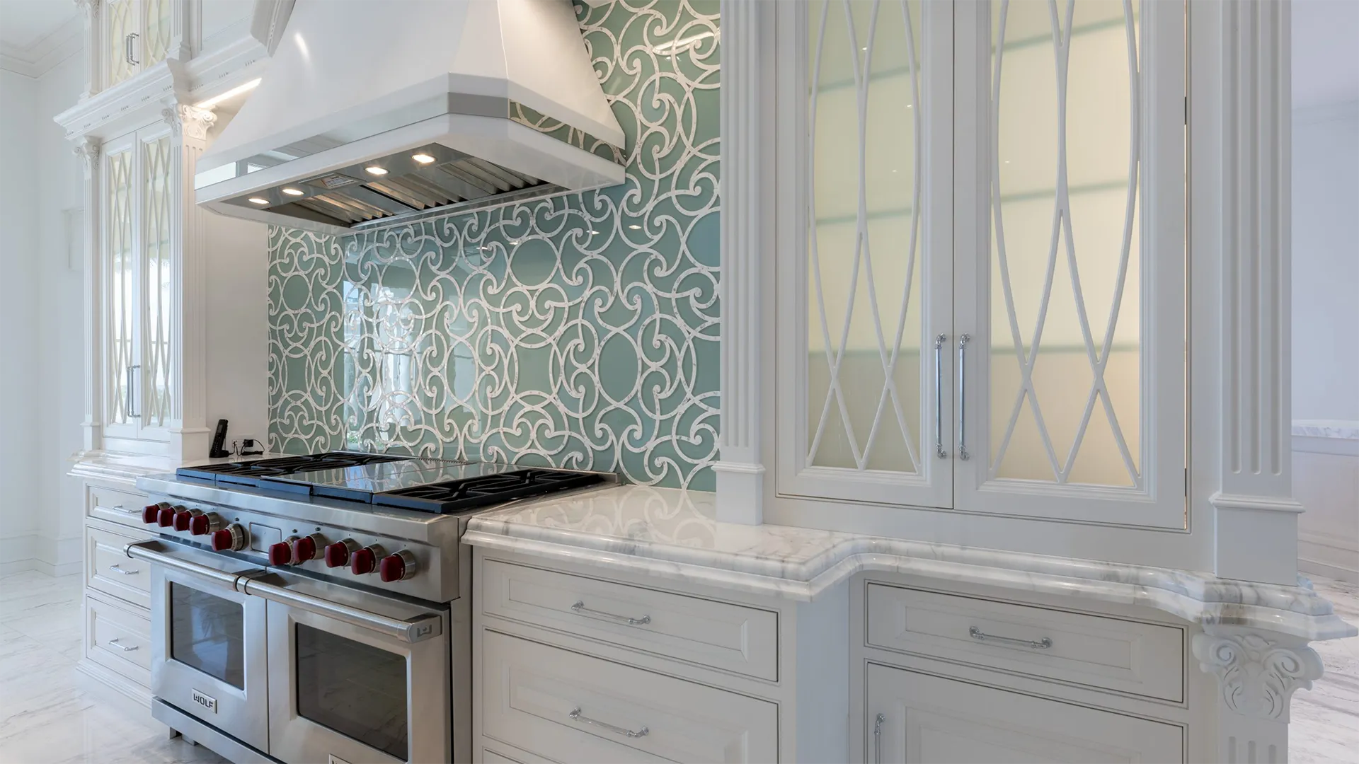 Kitchen with immaculate white cabinets complemented by a captivating blue and white patterned wall.