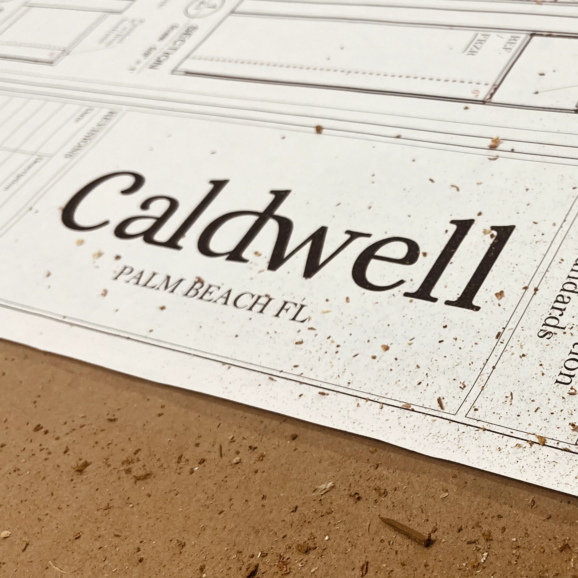 Piece of blueprint of furnishings with Caldwell logo visible on a dusty table.