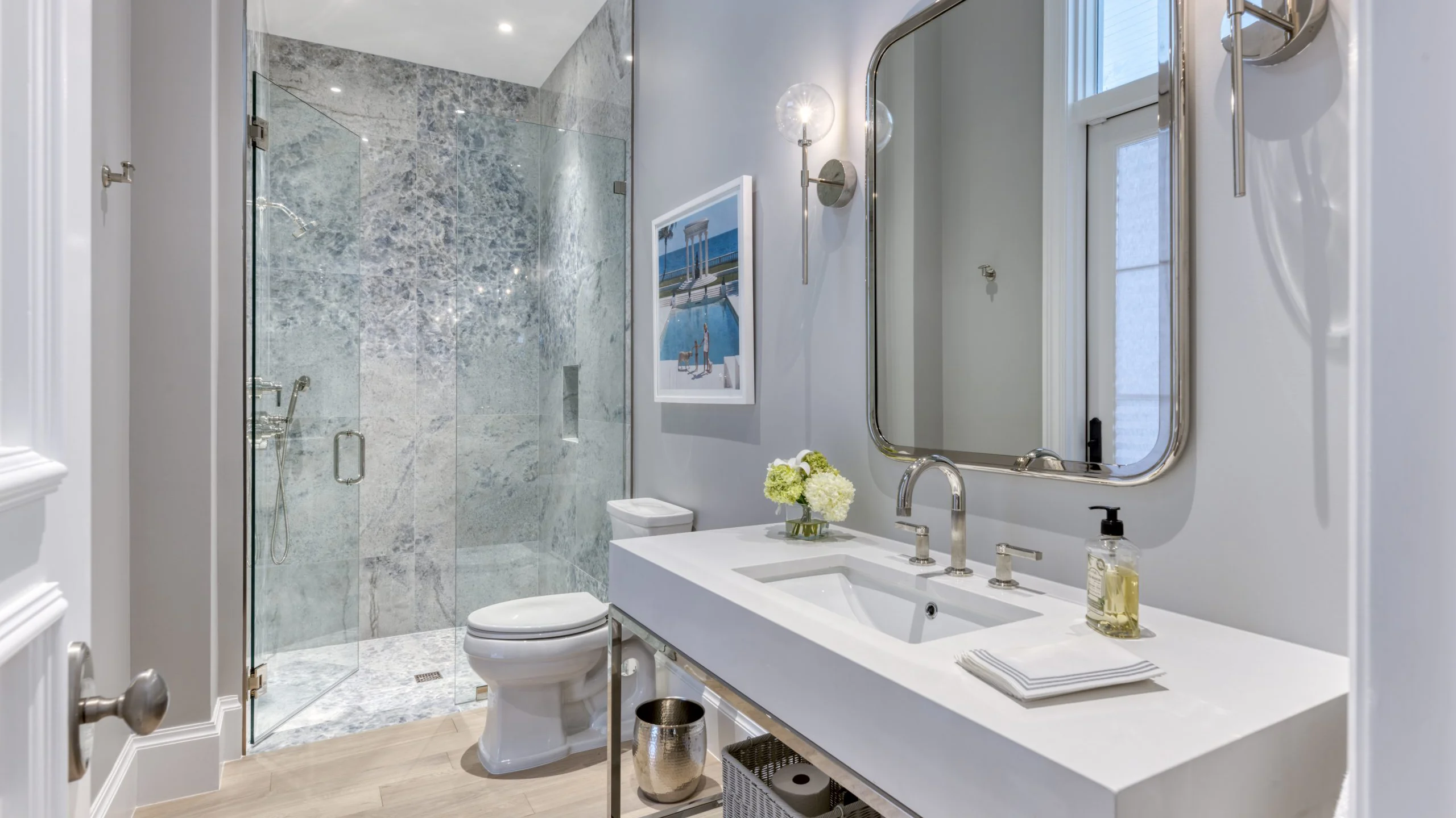 Luxurious bathroom featuring elegant marble walls and a sleek glass shower door.