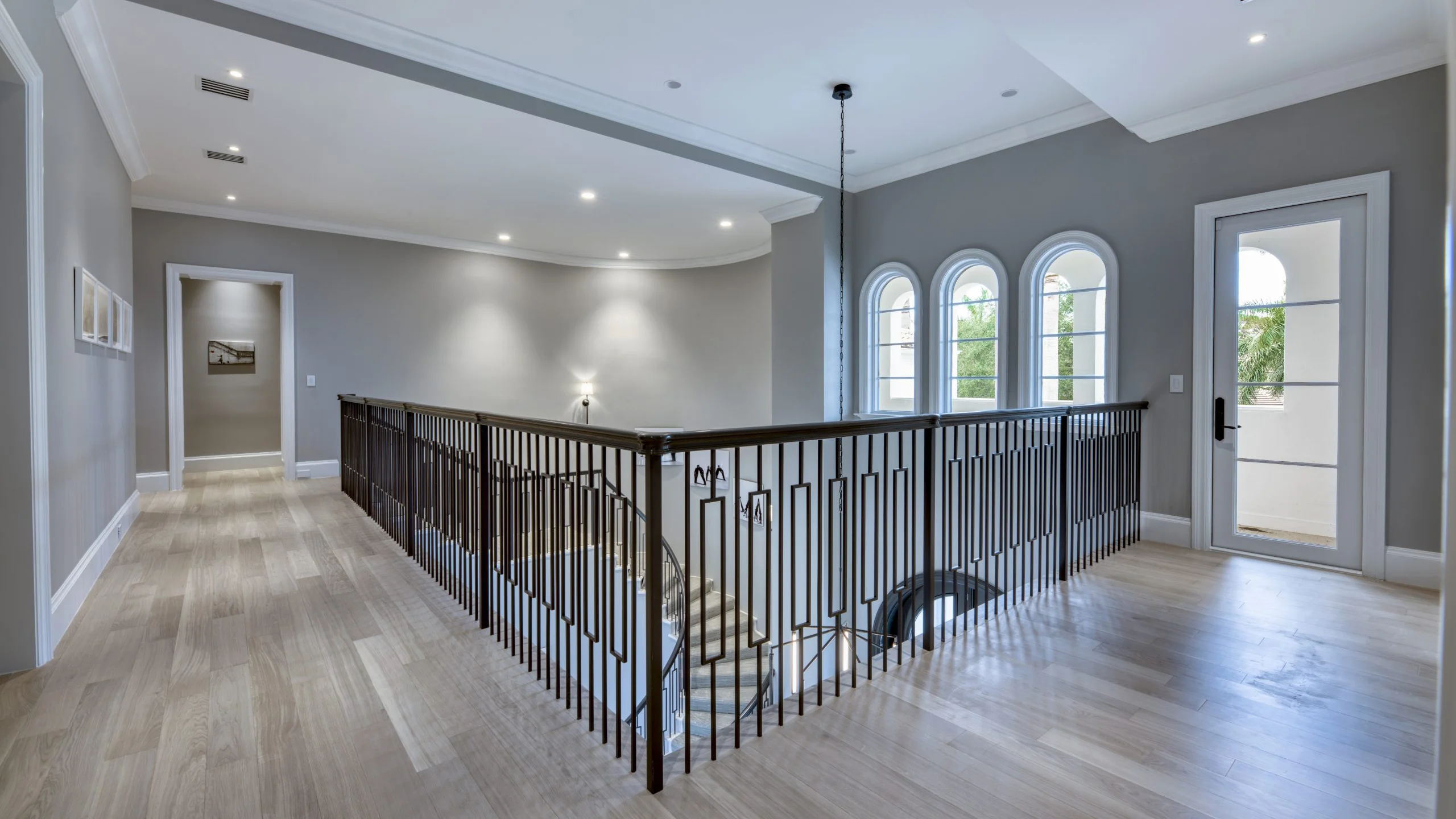 Hallway adorned with a staircase and black railing.