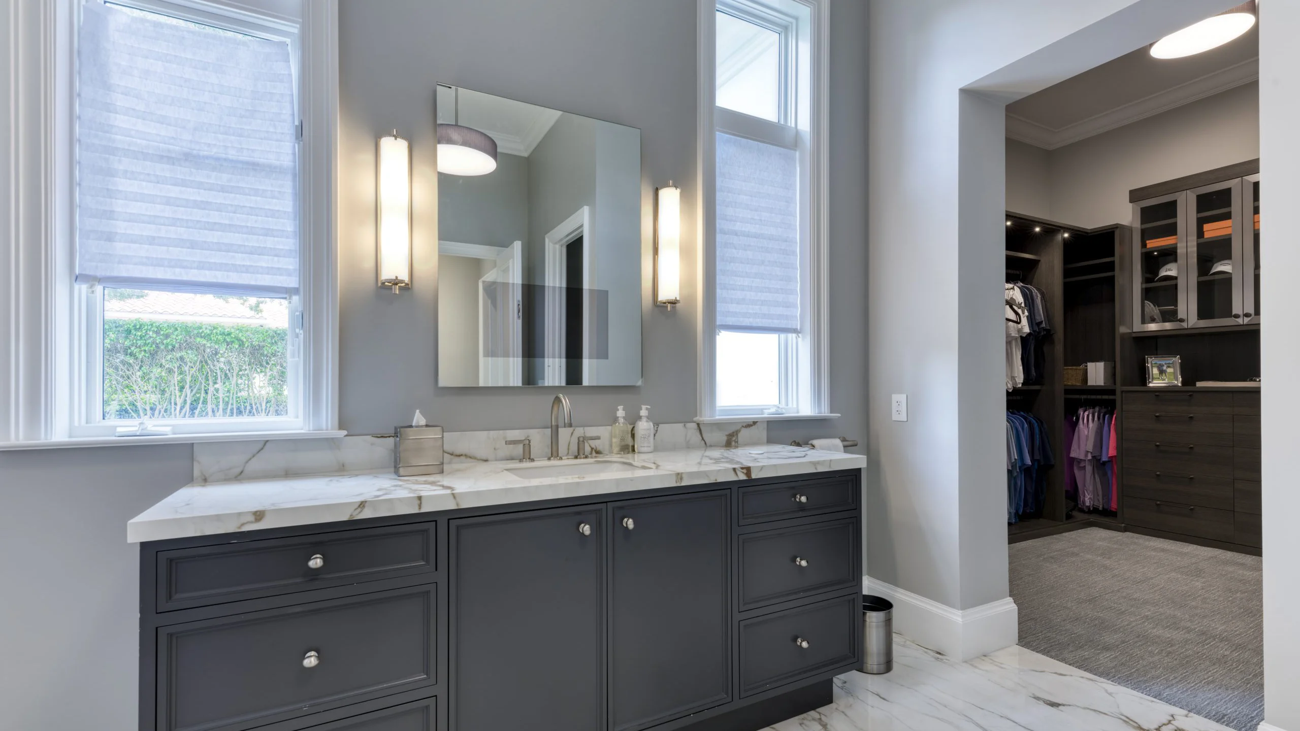 Bathroom featuring a walk-in closet and an elegant vanity for enhanced functionality and style.