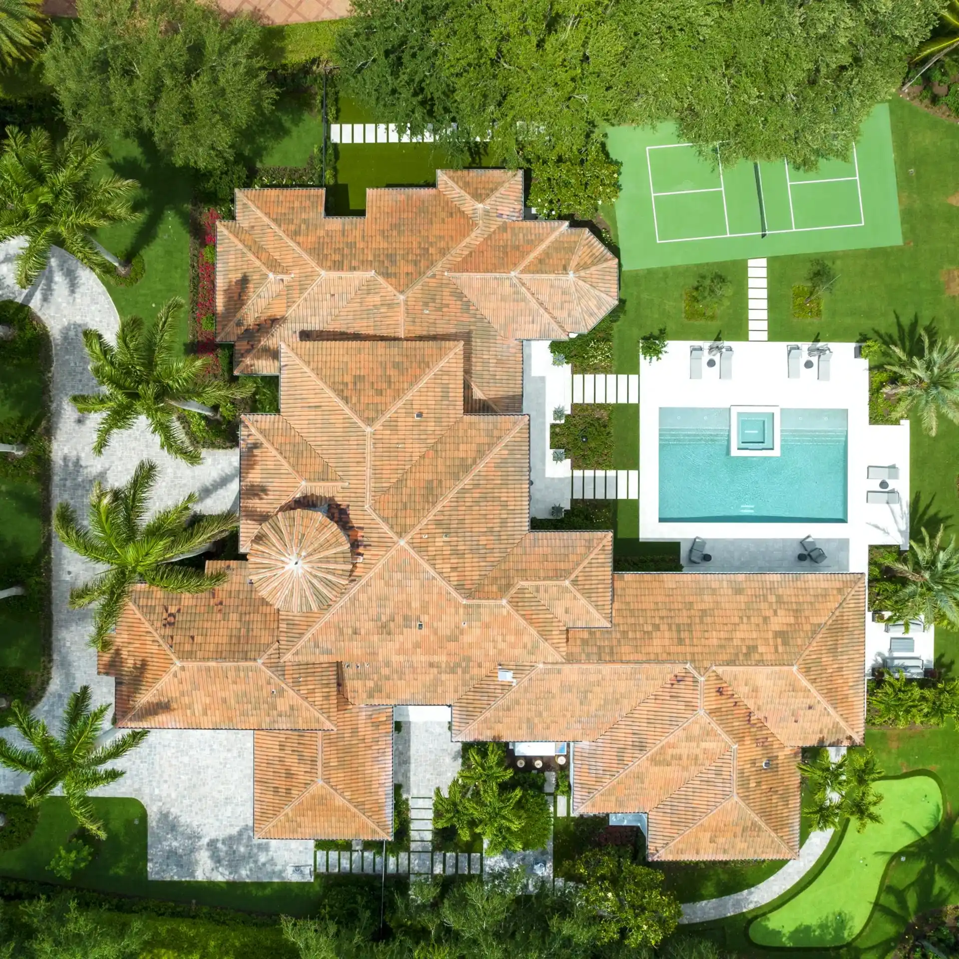 Aerial image of a large Modern Mediterranean style home, featuring a glistening pool, surrounded by lush gardens and sophisticated architecture.