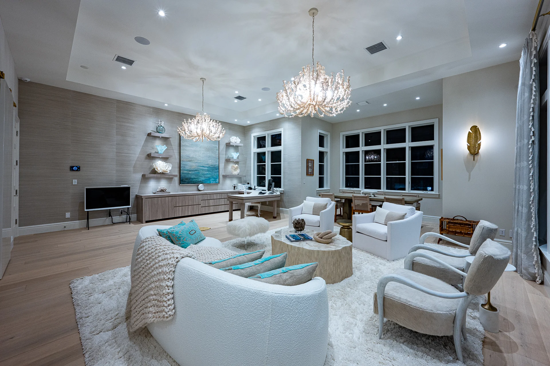 Soothing living room featuring white furnishings, a luxurious chandelier, and soft turquoise tones enhancing a peaceful ambiance.