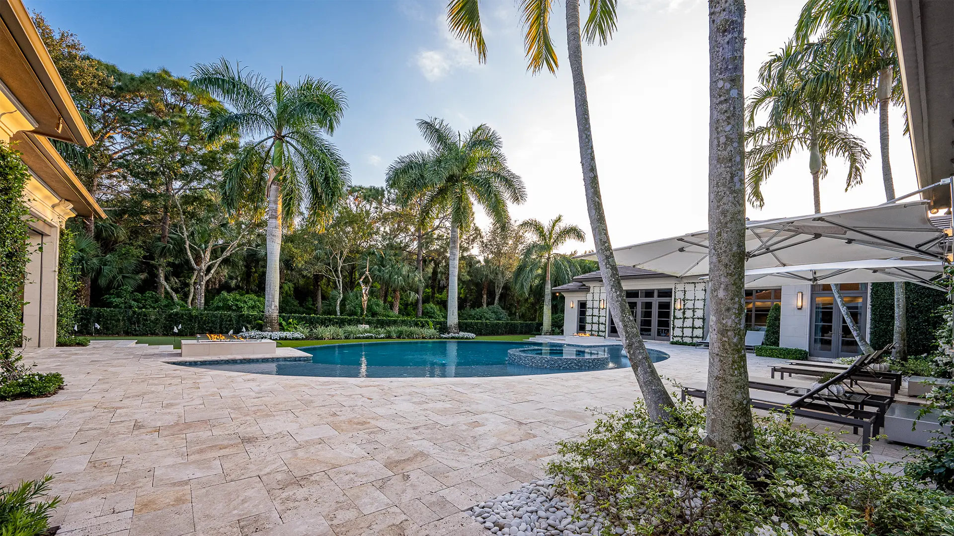 Opulent pool and patio encircled by lively palm trees, beckoning relaxation in the sunny atmosphere of Palm Beach.