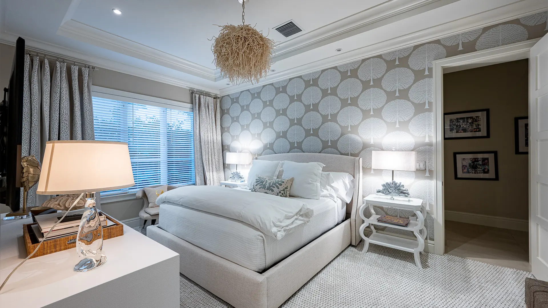 Serene bedroom featuring a white bed against elegant gray tree printed wallpaper.