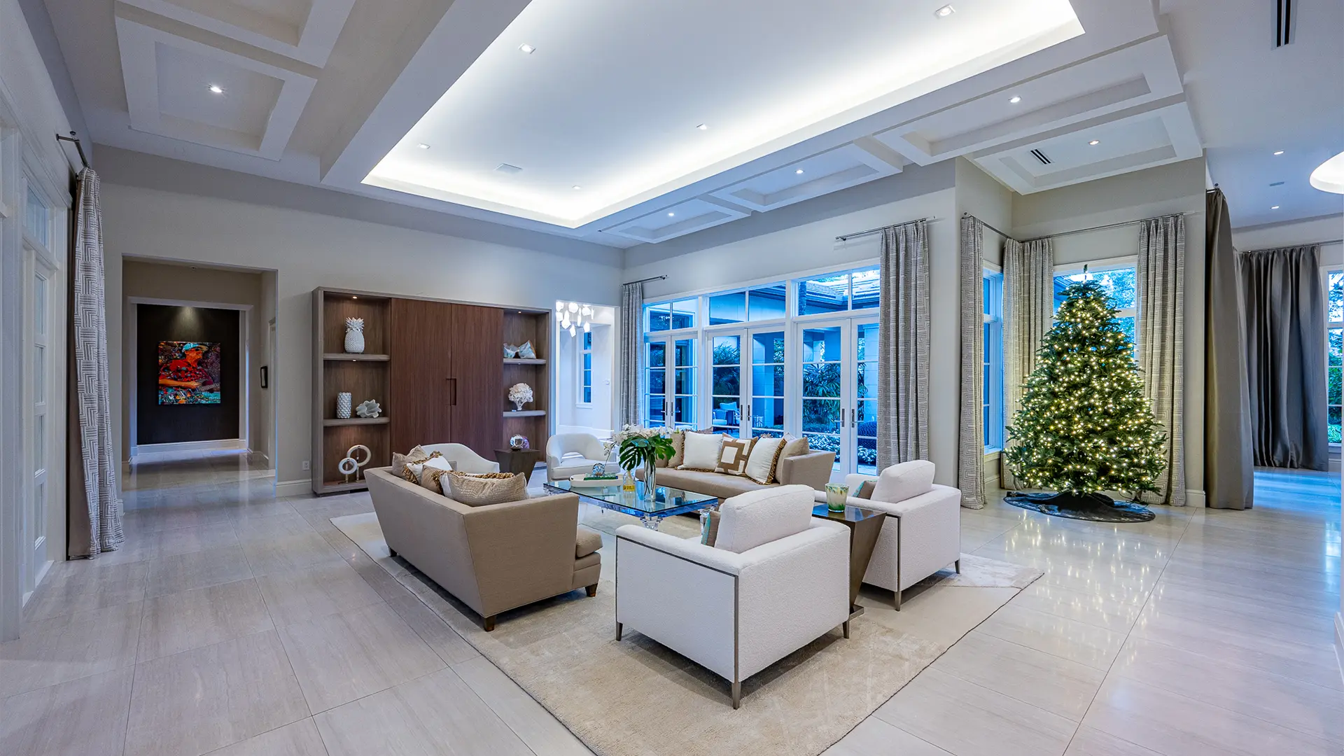 Luxurious living room with chic white decor, highlighted by a magnificent Christmas tree, exuding festive charm.