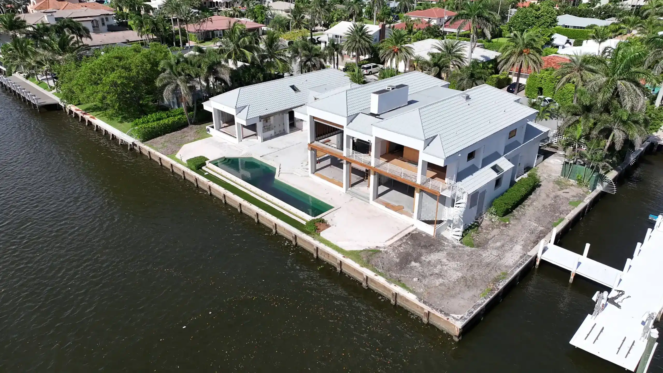 Aerial view of a spacious waterfront home surrounded by lush greenery and serene water.