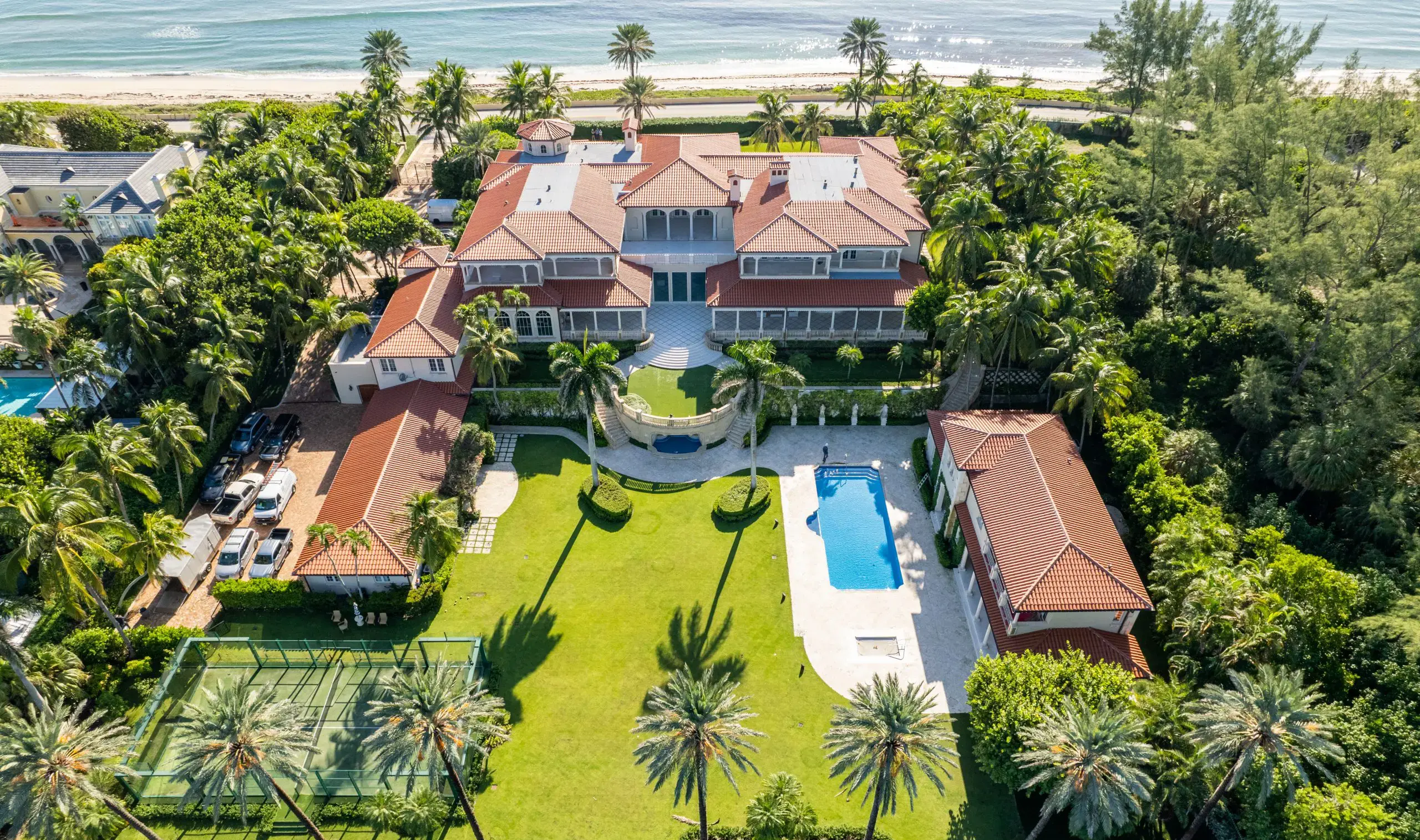 Aerial view of a New Mediterranean style luxury beach home in Palm Beach, showcasing its elegant design and proximity to the ocean.