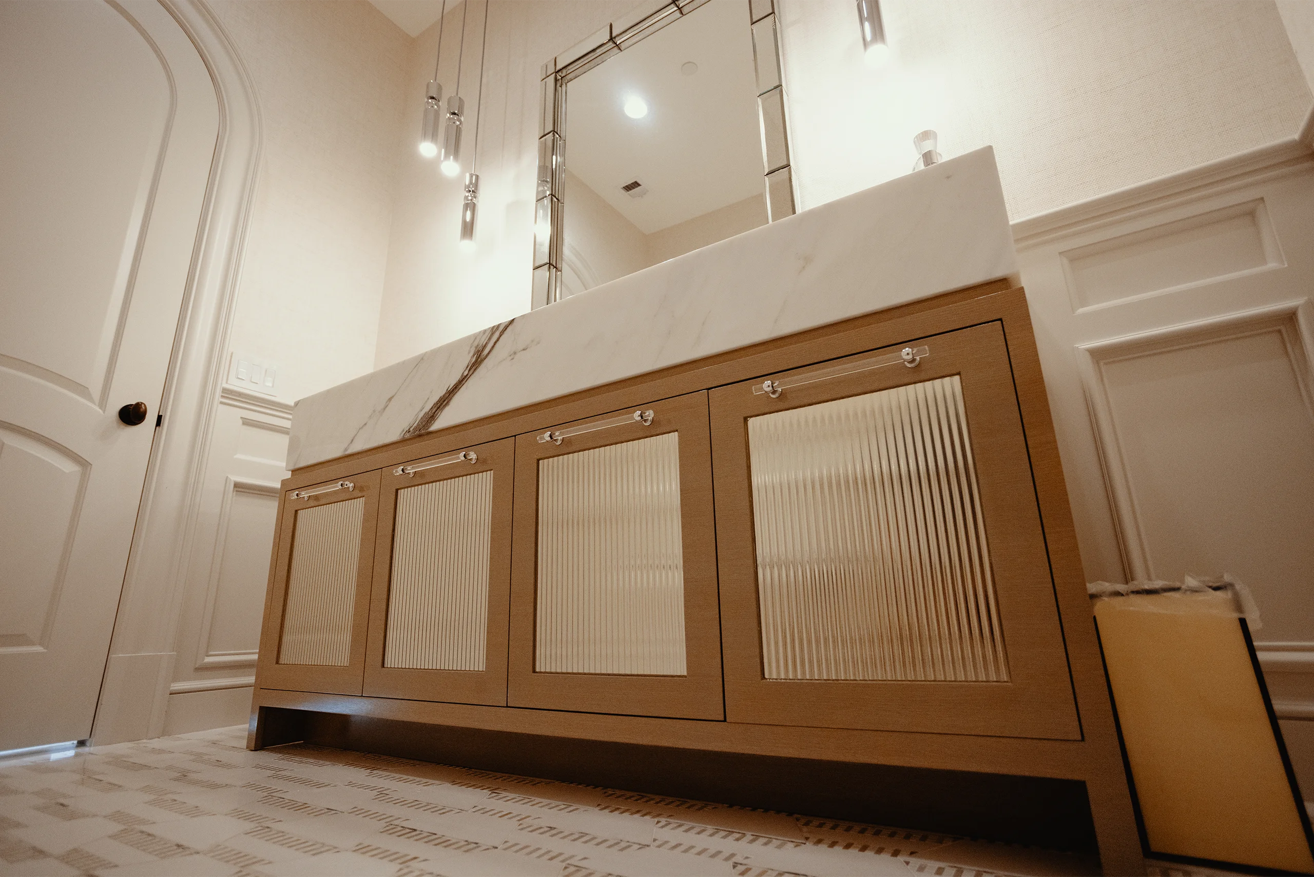 Custom-stained ash doors with inset fluted architectural mirrors topped with an 8-inch mitered Paonazzo Marble