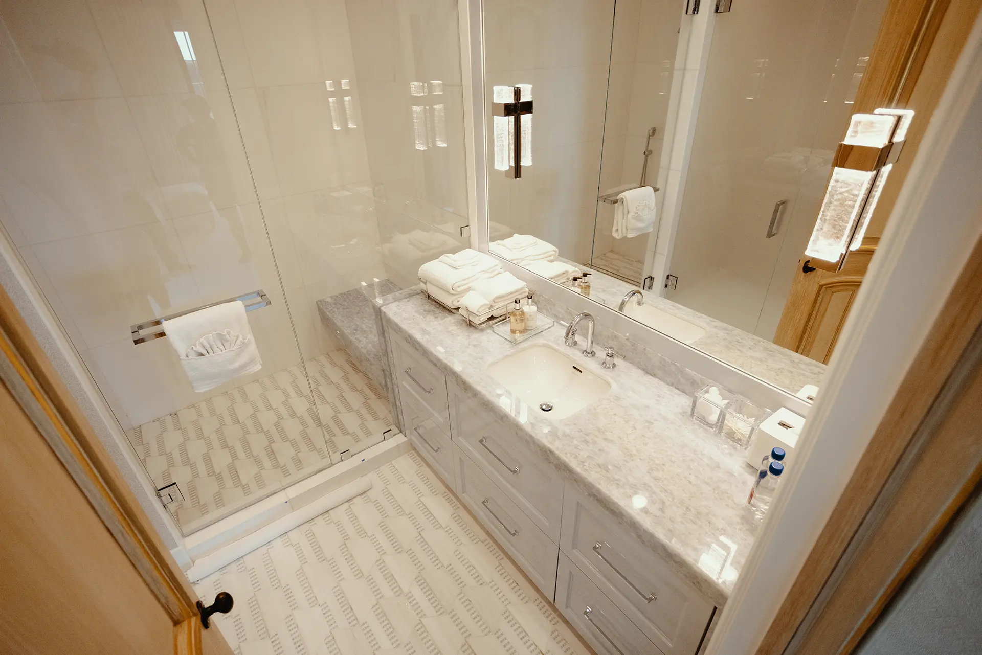 Luxurious bathroom featuring a spacious walk-in shower High Gloss Lacquer Vanity in Iced Slate, topped with Polished Calcite Blue Quartzite, and a Honed Sidetrack Bianco Dolomiti Mosaic flooring