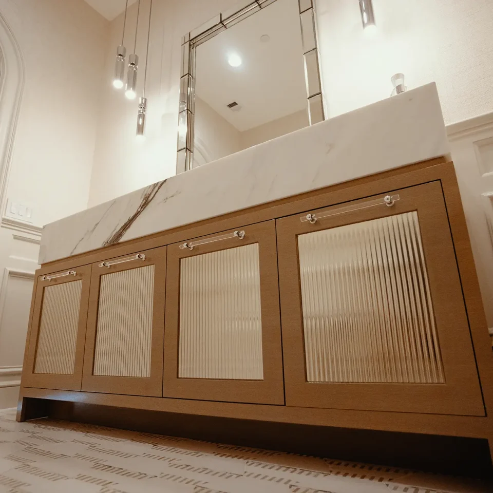 Custom-stained ash doors with inset fluted architectural mirrors topped with an 8-inch mitered Paonazzo Marble