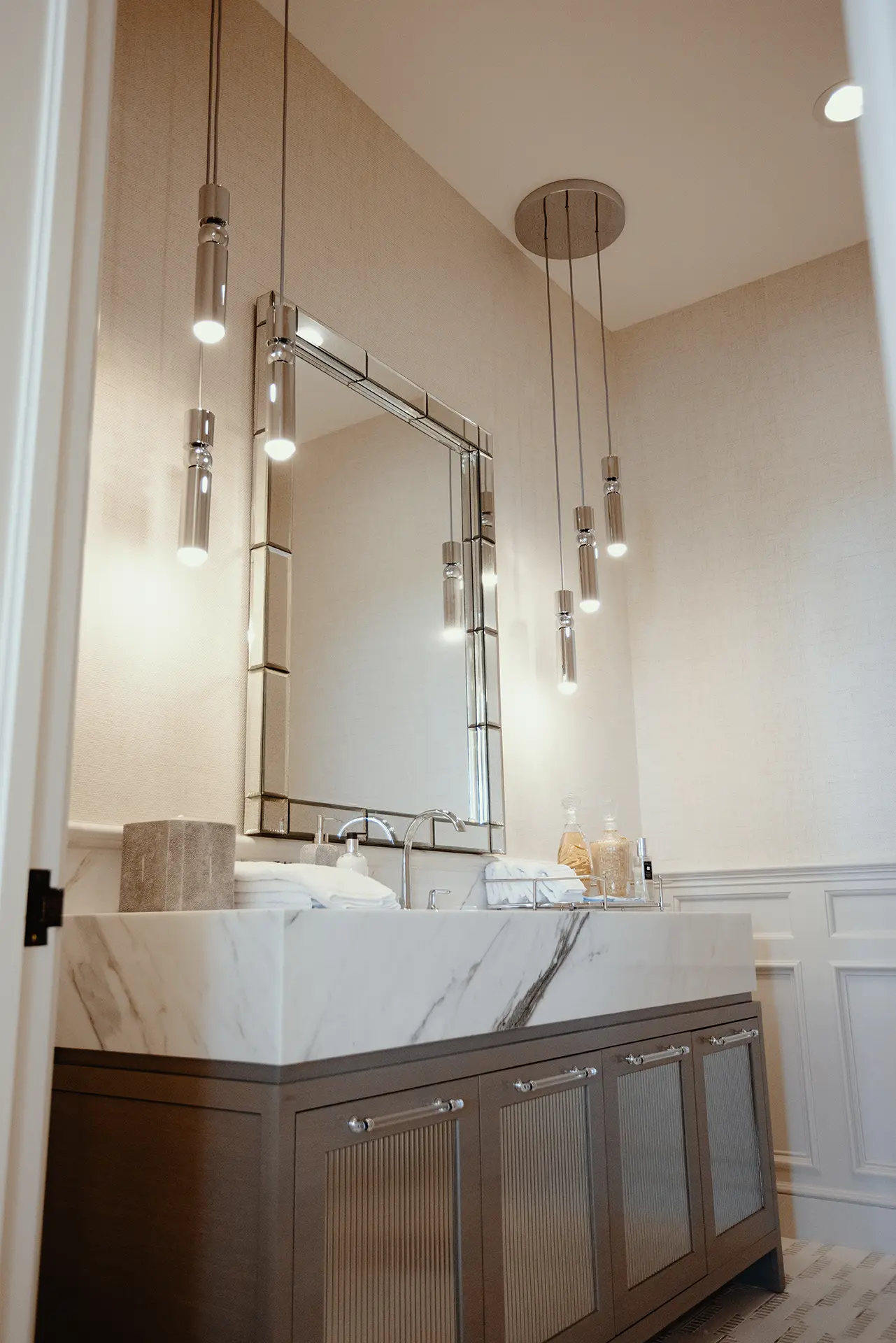 Custom-stained ash doors with inset fluted architectural mirrors topped with an 8-inch mitered Paonazzo Marble