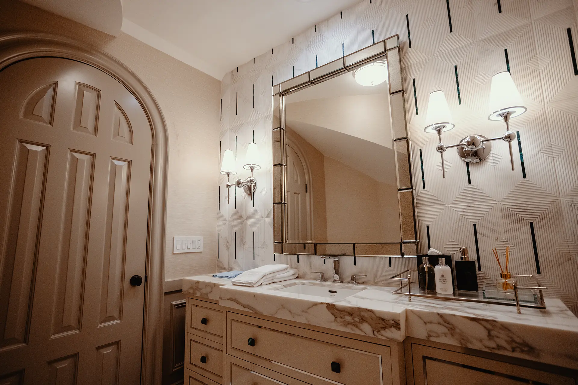 Luxurious bathroom featuring a High Gloss Lacquer Vanity in Iced Slate topped with a striking 4-inch mitered Calacatta marble, backed by and accent wall of Empire Volakas White with Malachite